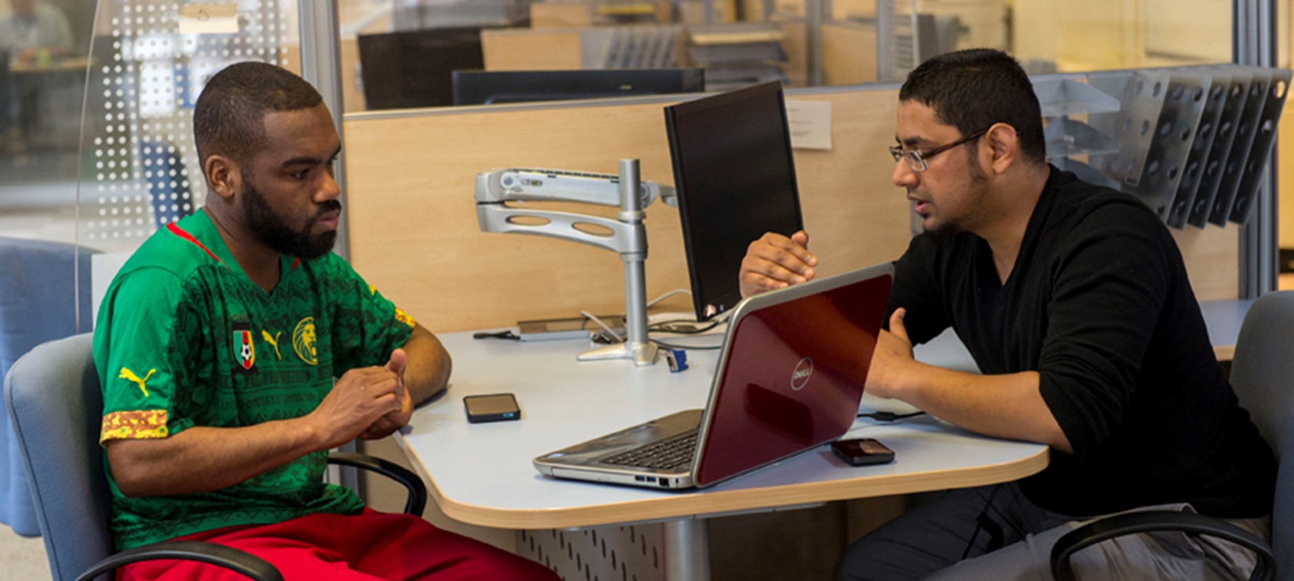 Two men sitting at the table looking at a laptop